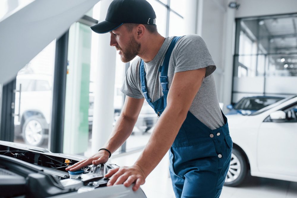 Mechanik przy otwartej masce podczas wymiany akumulatora